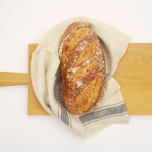 Pain meule blanc de Carrément Bon, pain rustique à la farine de froment blanche, offrant une croûte dorée et une mie aérée, idéal pour accompagner vos repas ou vos tartines du matin.
