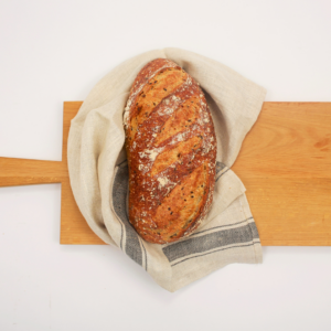Meule de pain multi-céréales de Carrément Bon, pain rustique à base de farine de froment, seigle et céréales variées, offrant une croûte épaisse et une mie aérée, idéale pour un goût riche et nourrissant.